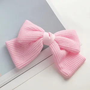 Close-up of pink knitted bow hair clip, delicate woven texture detail, elegant hair accessory