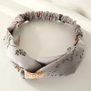 Gros-plan sur le bandeau en tissu fleuri vintage avec nœud torsadé et élastique au dos.