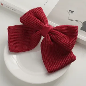 Close-up detail of red knitted bow hair clip texture and fabric craftsmanship showcase.