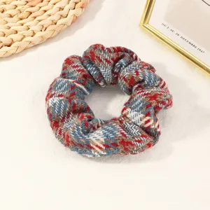 Detailed close-up of a cozy wool herringbone hair scrunchie with blue and red tones.