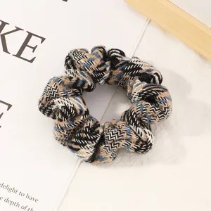 Detailed close-up of a blue plaid knit hair scrunchie, chic patterned hair accessory for daily use.