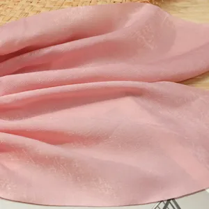 Primo piano dettagliato della texture del tessuto in raso di seta rosa, design elegante.
