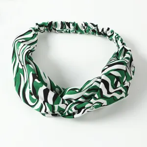 Detailed close-up of the green and black abstract print elastic headband fabric texture.