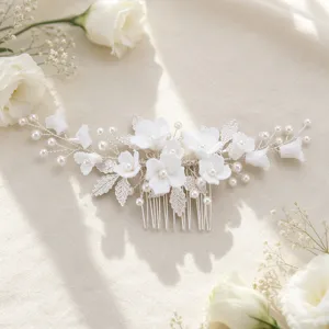 Detailed shot of white ceramic flower bridal hair comb with pearls and silver wire, floral accent.