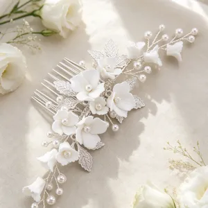 Detailed view of handmade bridal hair comb featuring white ceramic flowers, leaves, and pearls.