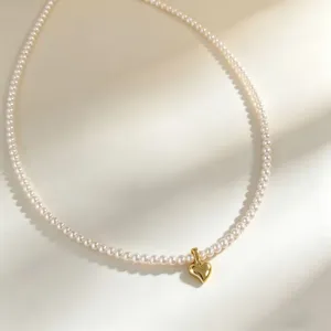 Delicate pearl necklace with a small gold heart pendant, showing exquisite close-up details.