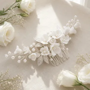 Exquisite detail shot of handmade bridal hair comb with white ceramic flowers, pearls and silver leaves.