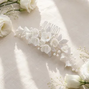 Close-up detail of white ceramic flower pearl bridal hair comb on fabric background.
