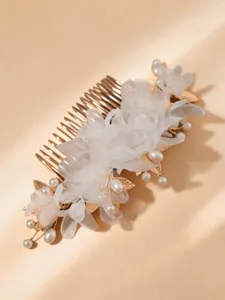 Detailed view of gold bridal hair comb featuring white organza flowers and pearls.