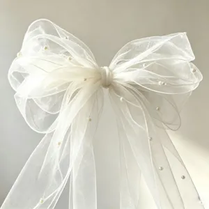 Fermaglio per capelli con fiocco in organza bianca e perle, dettaglio accessorio sposa vintage.
