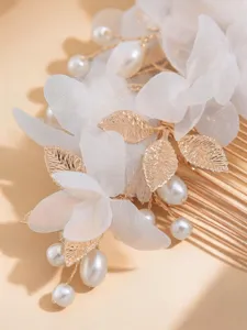 Exquisite bridal hair comb featuring white floral petals, gold leaves, and pearls for wedding.