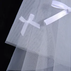 White bridal veil detail shot showing soft tulle fabric and cute bow decoration for wedding.