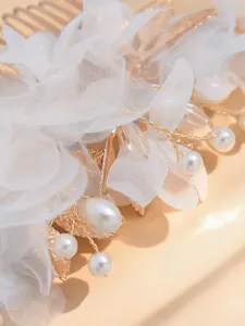 Exquisite detail of white floral hair comb with pearls and gold leaves for bridal wedding.
