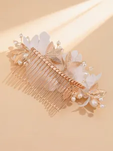 Detailed close-up of the gold bridal hair comb featuring delicate metal leaves and pearls.