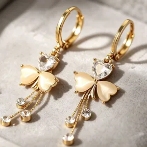 Gold-tone dangle earrings with heart stones, clover charms, and delicate sparkling crystal chains.