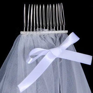 Detailed view of white bridal veil with silver comb and bow, perfect for wedding photography.