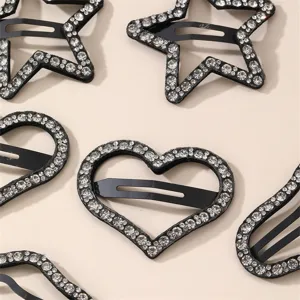 Detailed close-up of sparkling rhinestone hair clips in star and heart shapes, chic black design.