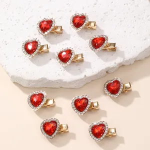Close-up detail of sparkling red heart rhinestone duckbill hair clips with gold metal base.