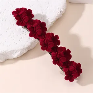 Detailopname van een donkerrode fluwelen bloem haarspeld met gedetailleerde gestructureerde bloemen.
