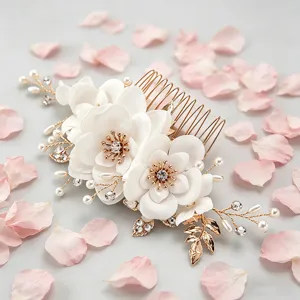 Elegant gold bridal hair comb detail with white fabric flowers, pearls and sparkling rhinestones.