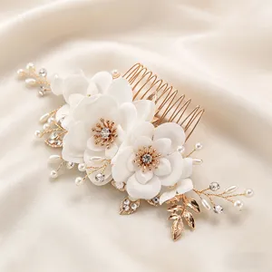Detailed view of elegant bridal hair comb with white fabric flowers, pearls, and rhinestones.
