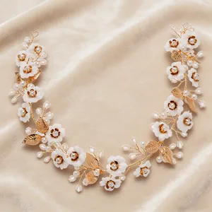 Close-up detail of a delicate gold bridal hair vine with white flowers, pearls and crystals.