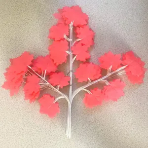 Detail view of artificial red maple leaf branch, plastic plant decor for autumn and home.