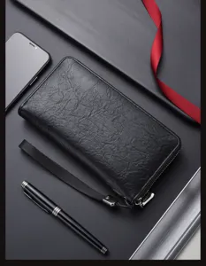 Portefeuille long homme en cuir noir avec fermeture éclair, dragonne et grand rangement.
