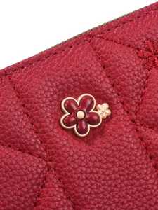 Red quilted long wallet for women with elegant metal flower decor and stylish zipper closure.