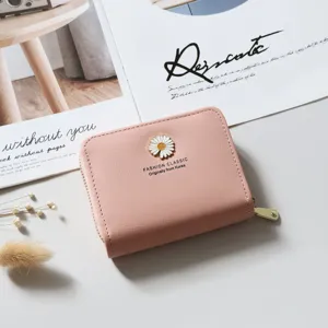 Close-up detail of the pink leather short wallet with cute daisy metal charm and zipper closure.