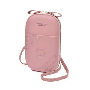 Detailed view of pink crossbody phone bag featuring cute embroidered bear and bow detail.