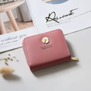 Close-up detail of the pink leather short wallet featuring a cute white daisy metal emblem.