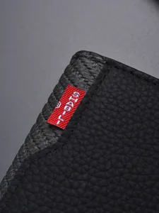 Portafoglio da uomo in pelle nera martellata con etichetta rossa, design minimal.