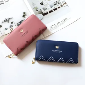 Long zip wallet detail view showing smooth PU leather texture, metal heart charm, and neat stitching.