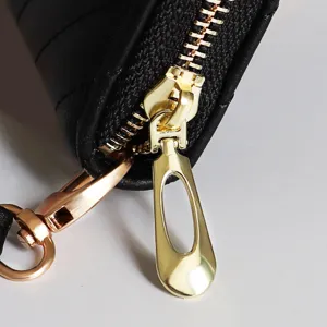 Nahaufnahme des luxuriösen Gold-Metall-Reißverschlusses an der schwarzen Damen-Brieftasche.