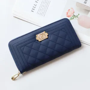Close-up detail of the dark blue quilted long wallet featuring a golden zipper and clasp.