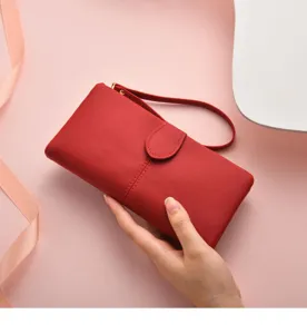 Close-up detail view of a stylish red long wallet with wrist strap and snap closure design.