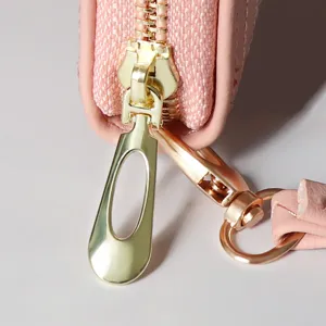 Women's long wallet metal zipper hardware detail, pink PU leather clutch purse accessory.