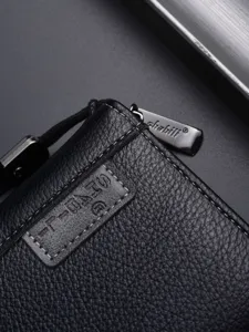 Portafoglio lungo da uomo in pelle nera con texture litchi, zip in metallo e vista di dettaglio.