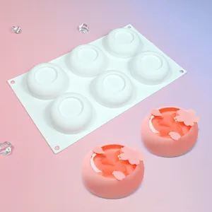 6 cavity white silicone mold with finished pink cherry blossom mousse cakes for baking desserts.