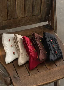 Close-up detail of retro cable-knit mid-tube cotton socks with cute floral embroidery.
