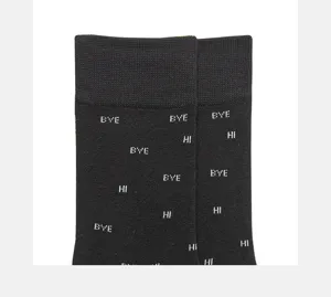 Close-up of black cotton crew socks featuring woven white letter patterns of bye and hi.