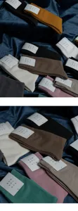Detailansicht einfarbiger Baumwollsocken in verschiedenen Farben, ordentlich auf Samt gestapelt.