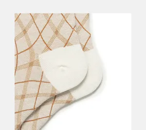 Close-up of women retro argyle knit socks, detailed beige and brown plaid pattern with white heel.