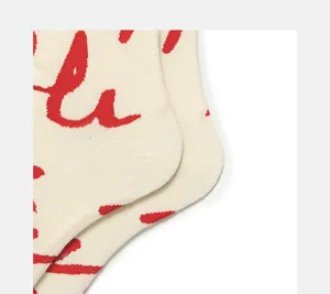 Detailed view of cream knit socks featuring a stylish red handwritten pattern design.