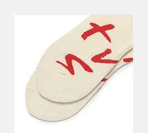 Beige knitted socks detail with red cross pattern, comfortable cotton fabric casual style.