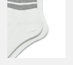 Detailed close-up of white cotton socks featuring classic grey stripes near the ankle.