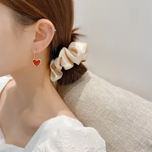 Primo piano dettagliato di eleganti orecchini a cerchio con cuore rosso indossati da modella.