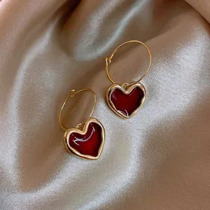 Vista dettagliata di eleganti orecchini a cerchio con cuore rosso placcato in oro.