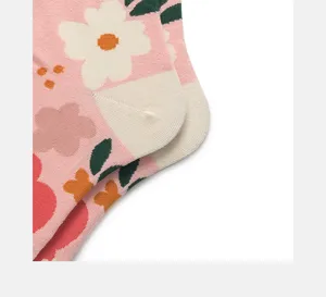 Close-up detail of pink cotton socks featuring cute white floral knit patterns and heels.